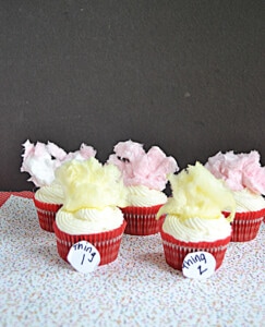 A bunch of cupcakes in red liners with yellow and pink cotton candy on top.