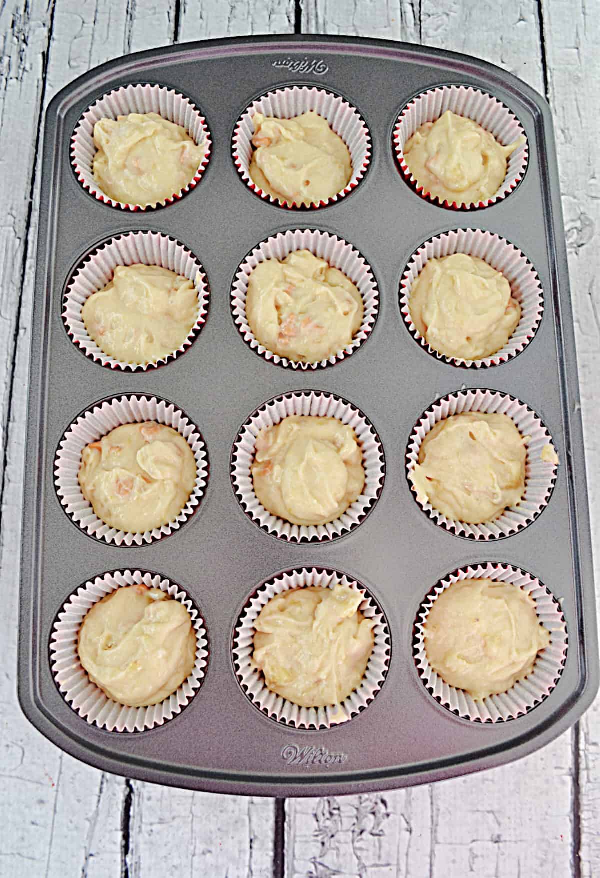 A muffin tin with batter in it.