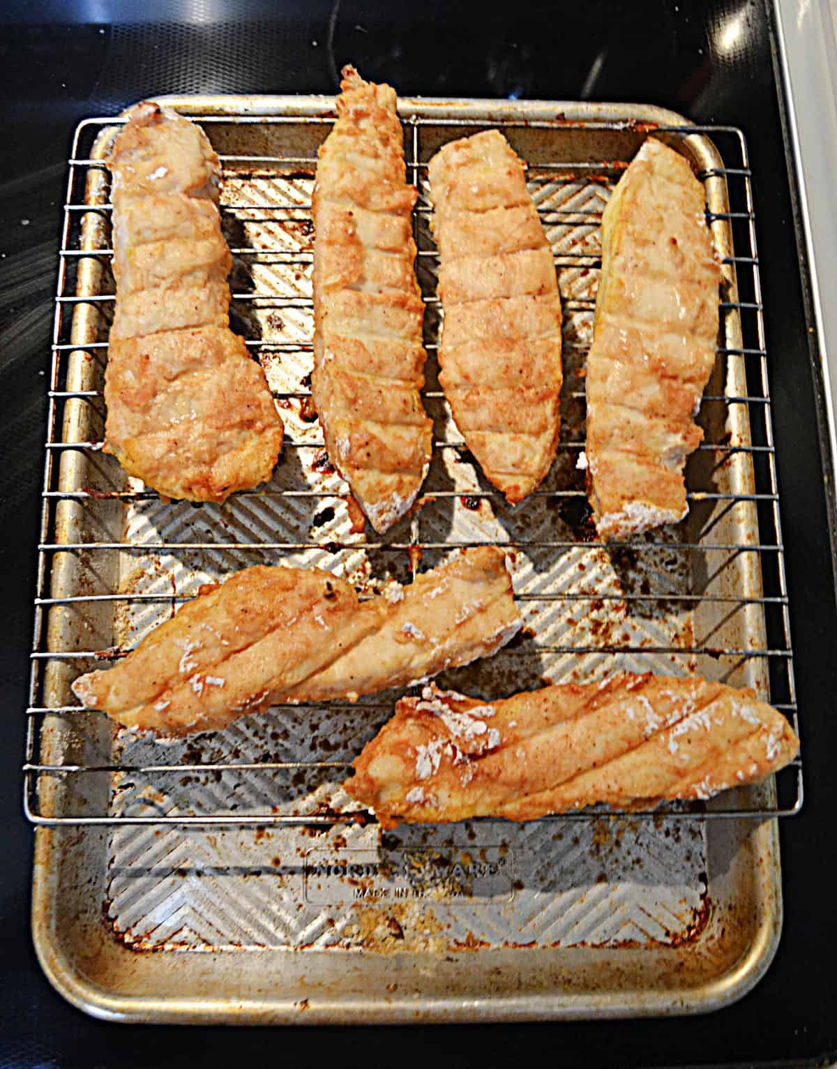 Chicken fingers on a wire rack on top of a baking sheet.