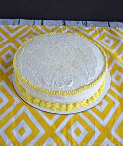 A Lemonade cake with white frosting and yellow piping.