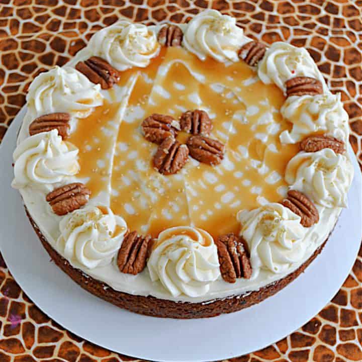 A butternut squash cake topped with frosting, caramel drizzle, and pecans.