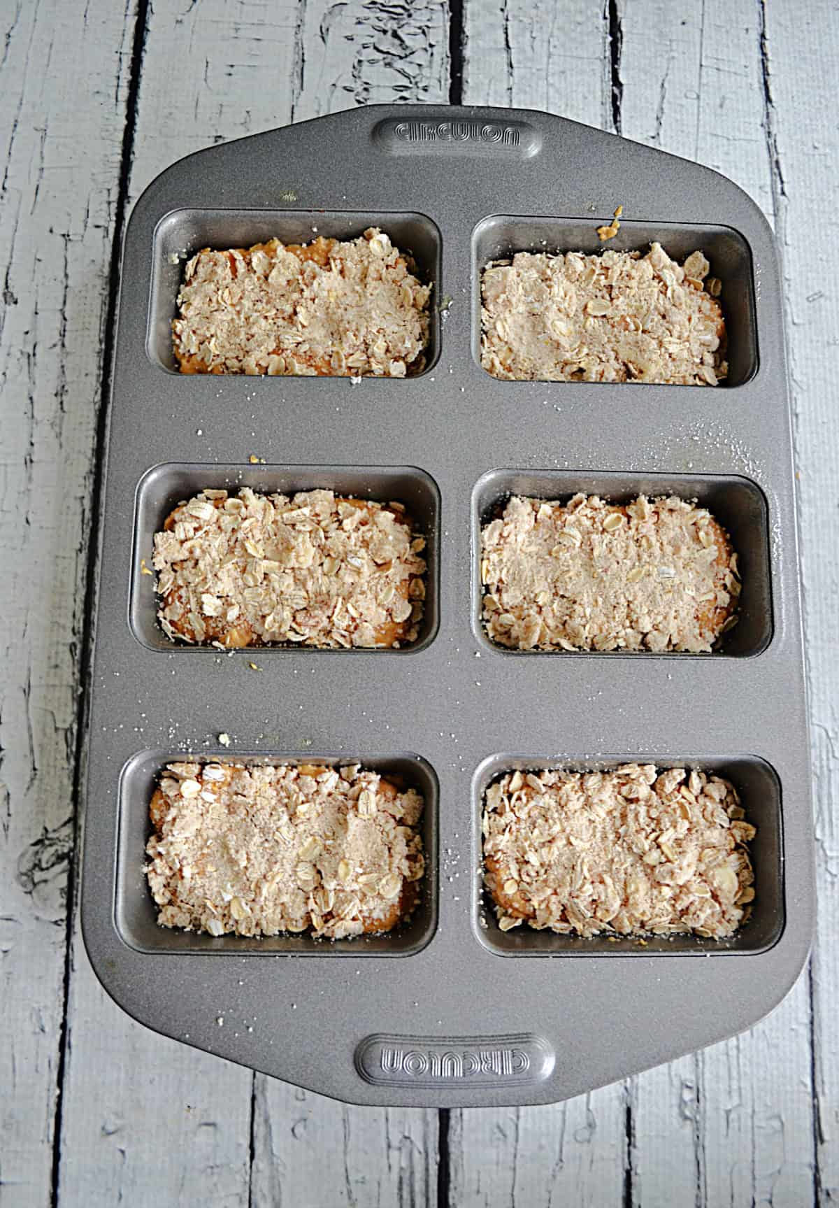 A pan with batter for 6 mini loaves of bread in it.