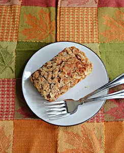 A plate with a mini loaf of bread on it and two forks.