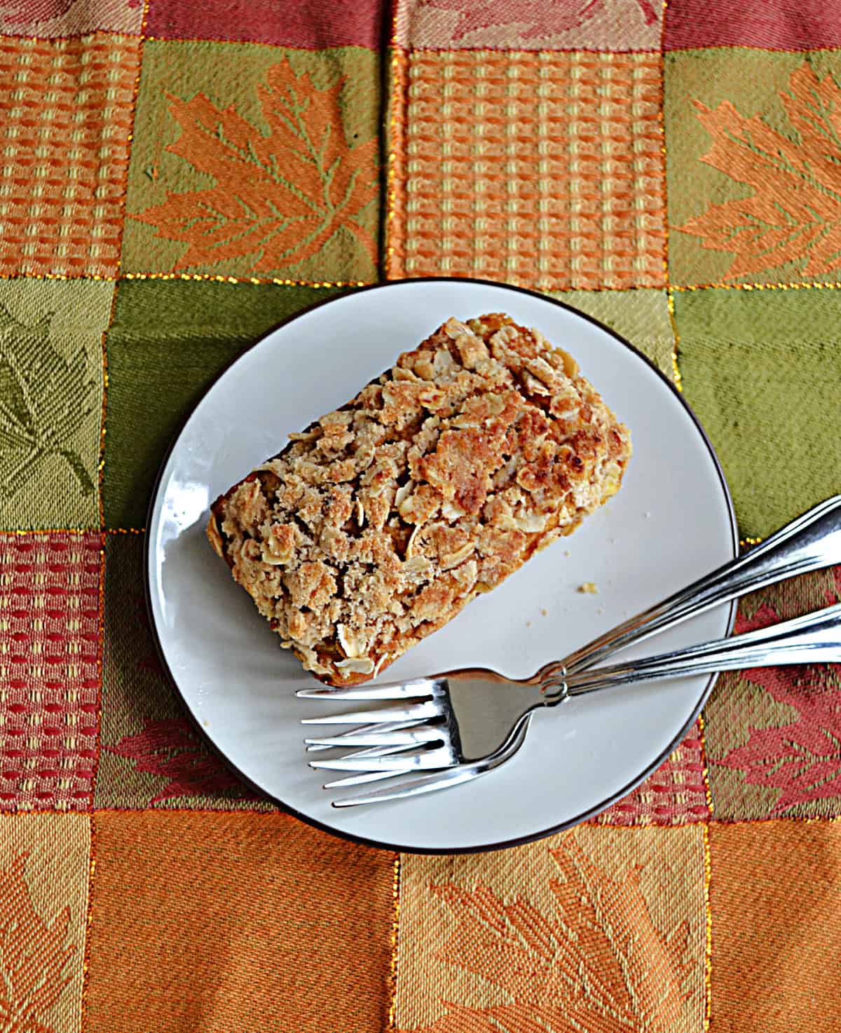 A plate with a mini loaf of bread on it and two forks.