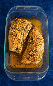 A baking dish with two turkey tenderloins that are golden brown.