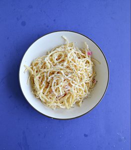 A bowl filled with pasta in a creamy lemon sauce topped with cheese.