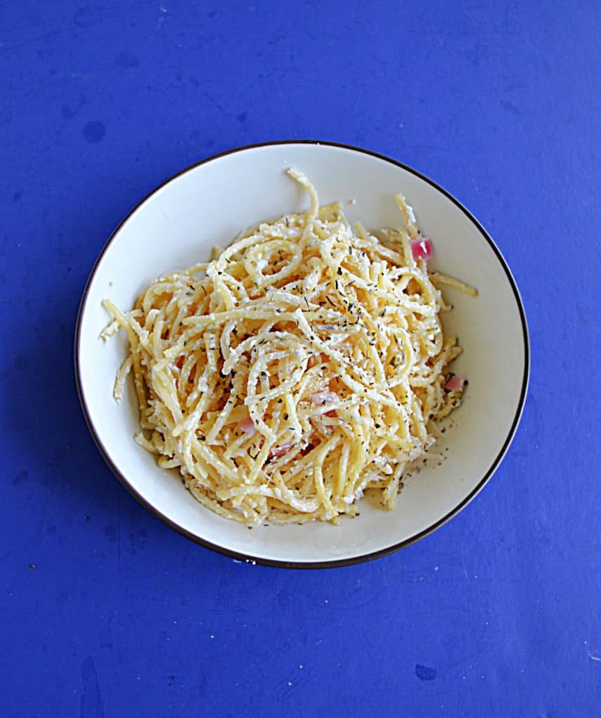 A bowl of spaghetti tossed with creamy lemon sauce and topped off with Parmesan cheese.