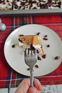 A close up of a piece of Cranberry Bliss Bar on a fork with a plate in the background.