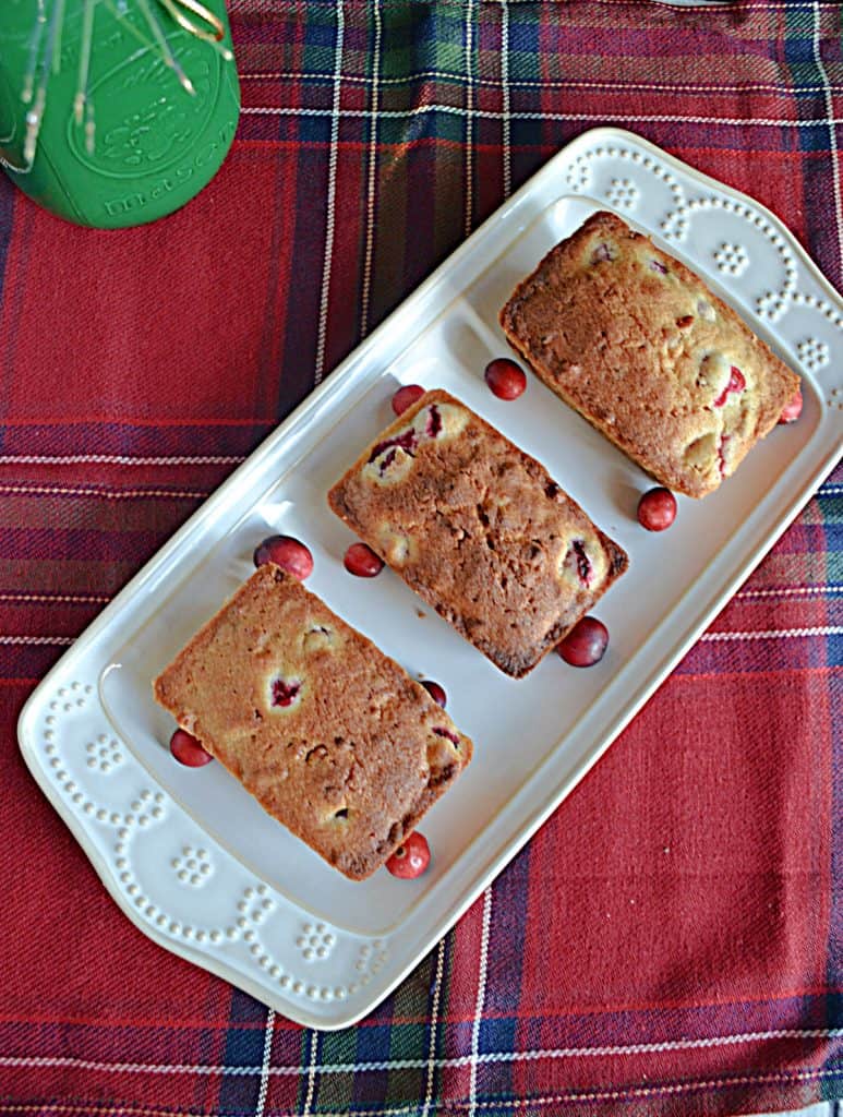 A platter with three mini cranberry pecan loaves on it. 