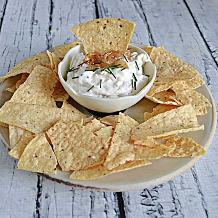 A plate of tortilla chips with a bowl of onion dip with a chip in it in the middle.