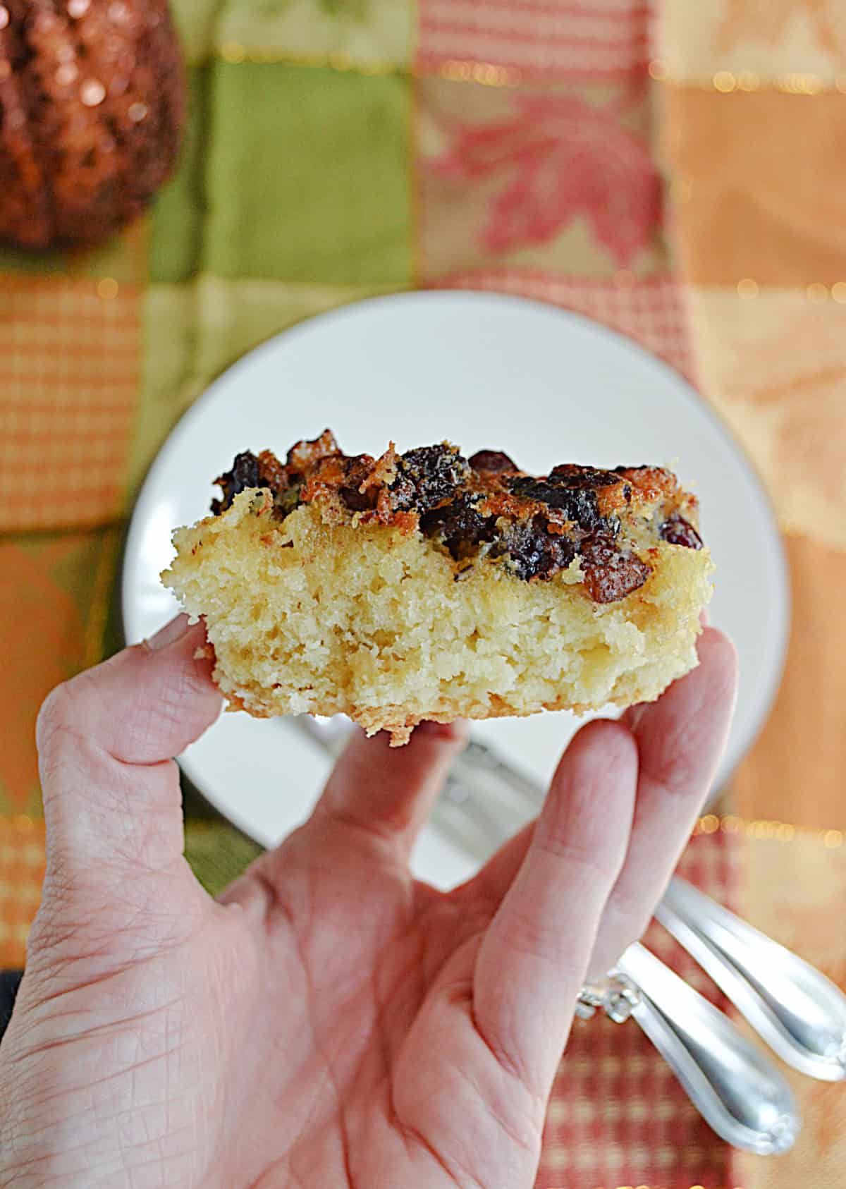 A hand holding a cranberry maple bar up close.