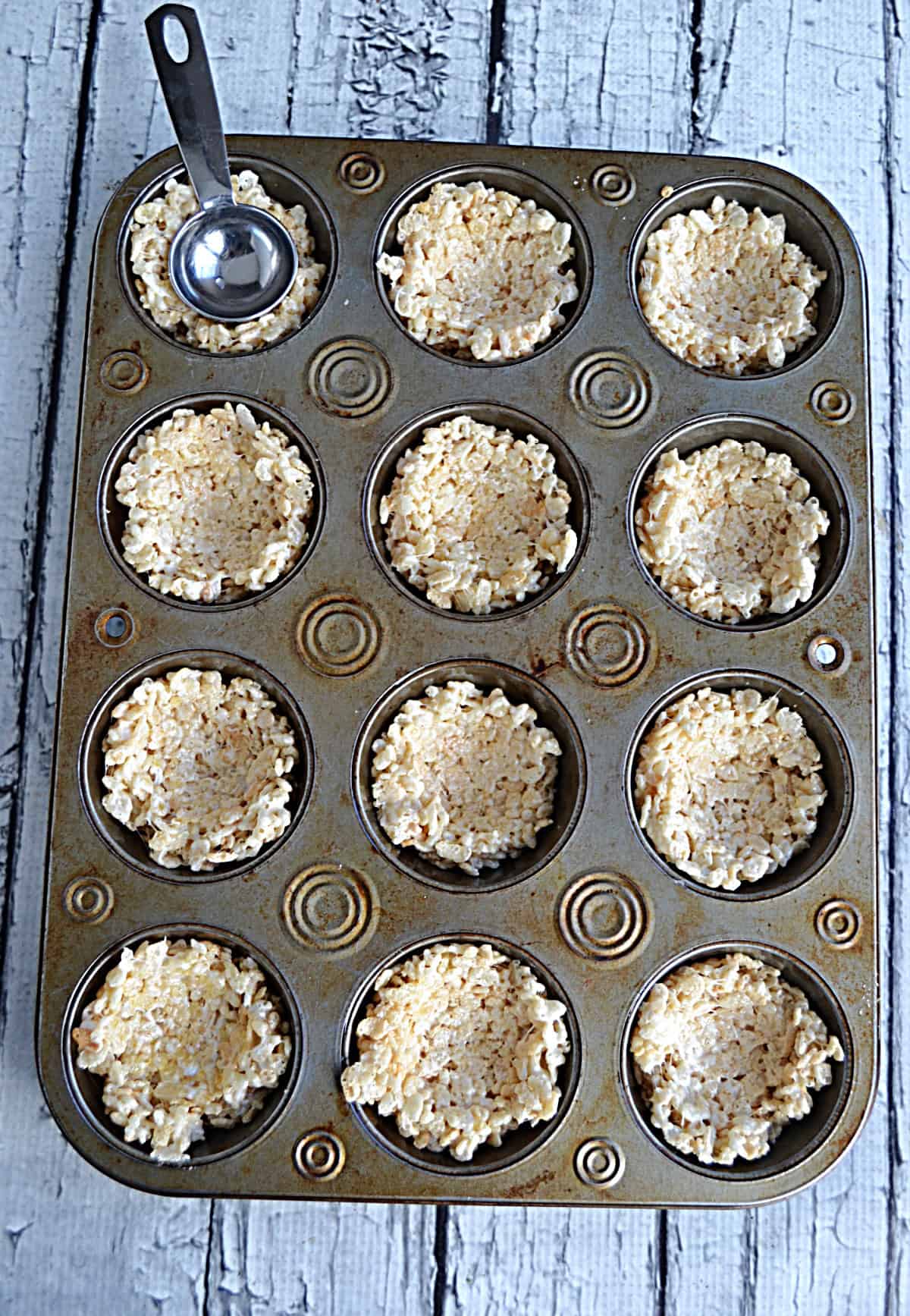 A muffin tin with rice krispies treats in it.