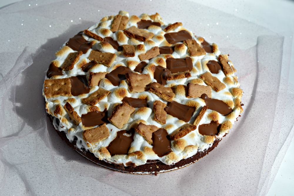 S'mores cake topped with browned marshmallows, graham crackers, and Hershey bar pieces