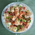 A bowl with Potato salad with chives, paprika, and bacon.