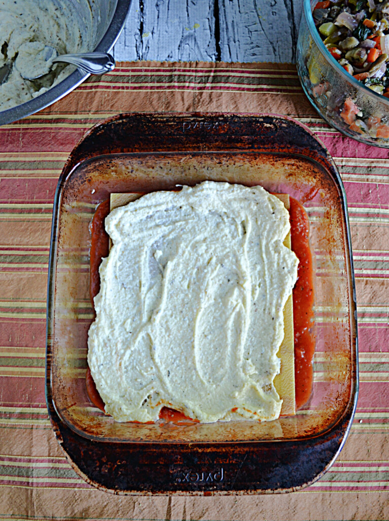 A pan with lasagna noodles topped off with ricotta cheese.