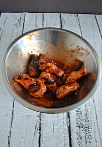 A bowl of crispy grilled wings tossed with hot sauce.