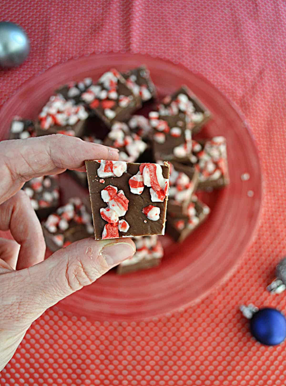 A hand holding a piece of peppermint fudge.