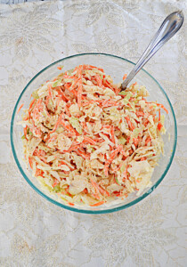A bowl of cole slaw with a spoon in it.