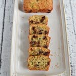 A mini chocolate chip zucchini loaf with one who loaf and one loaf sliced on a platter.