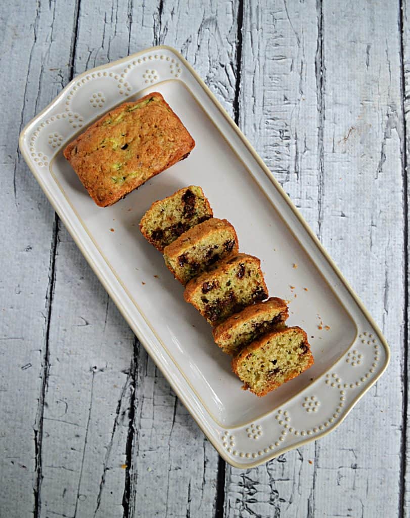 A platter with a mini chocolate chip zucchini bread and 5 slices of chocolate chip zucchini bread.
