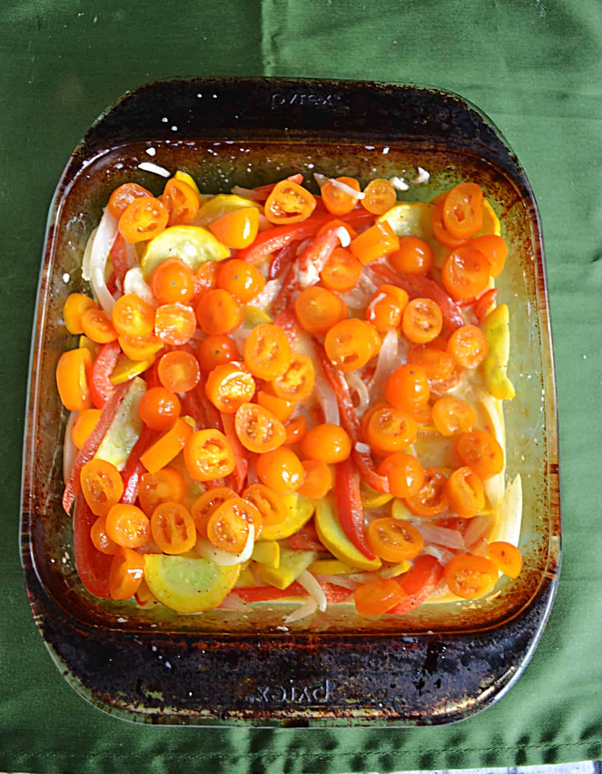 A baking dish full of vegetables including tomatoes and squash.