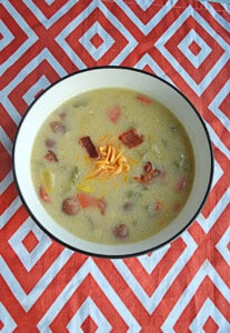 A bowl of soup with cheese and bacon on top.