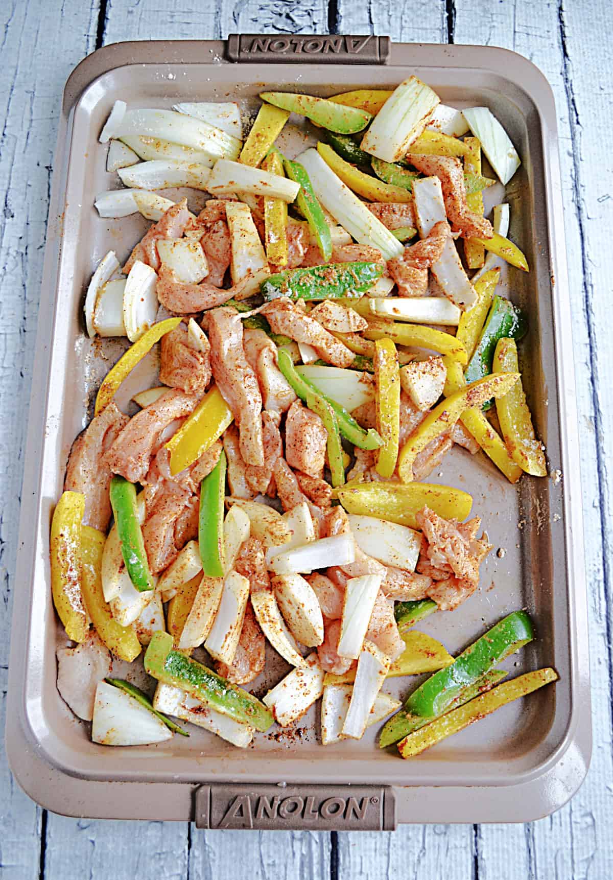 A sheet pan with chicken, peppers, and onions on it.