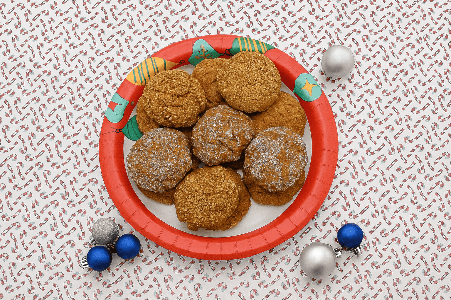 A plate of ginger cookies with small baubles around the plate.