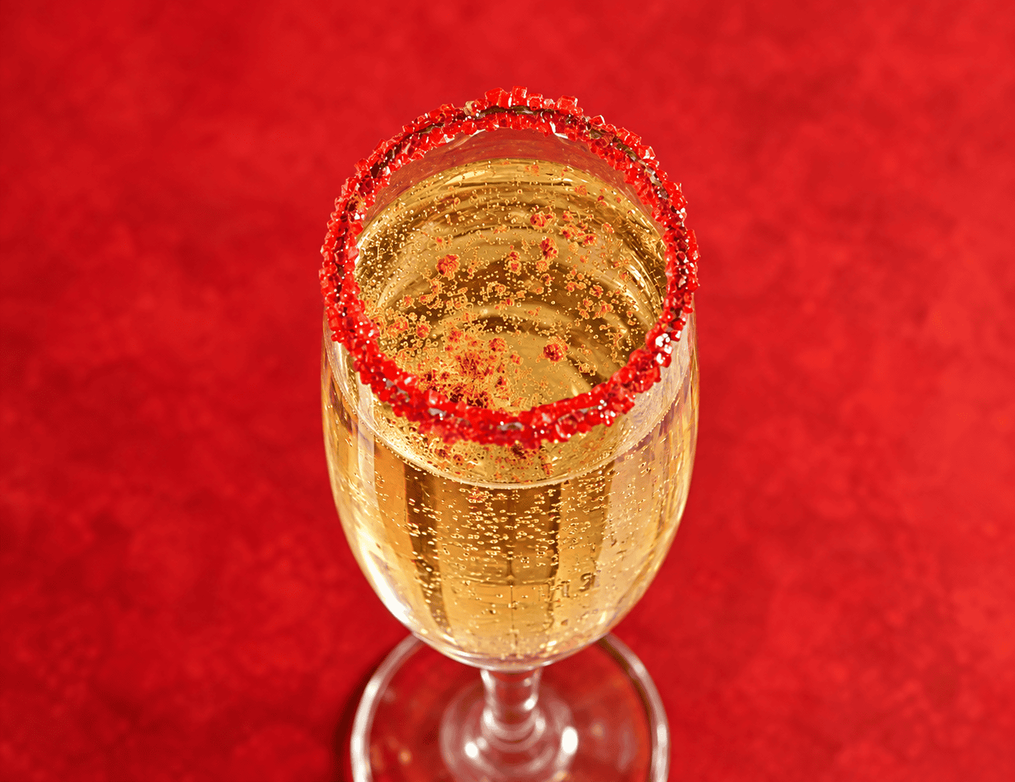 A top view of champagne glass rimmed with red sugar.