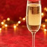 Pin IMage: Title, A champagne glass with twinkle lights in the back.