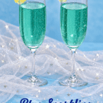 Pin Image: Title, two champagne glasses with a blue cocktail in them and an orange wedge on the rim.