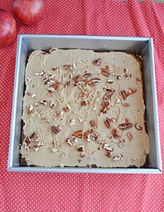A pan of blondies with caramel frosting and pecans on top.