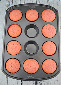 A muffin tin with pink velvet cupcakes.