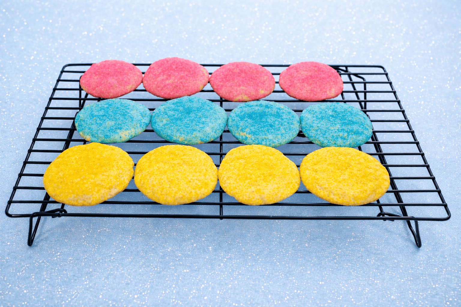 Pastel colored cookies on a cooling rack.