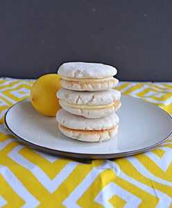 A plate with 3 lemon sandwich cookies stacked on top of each other.