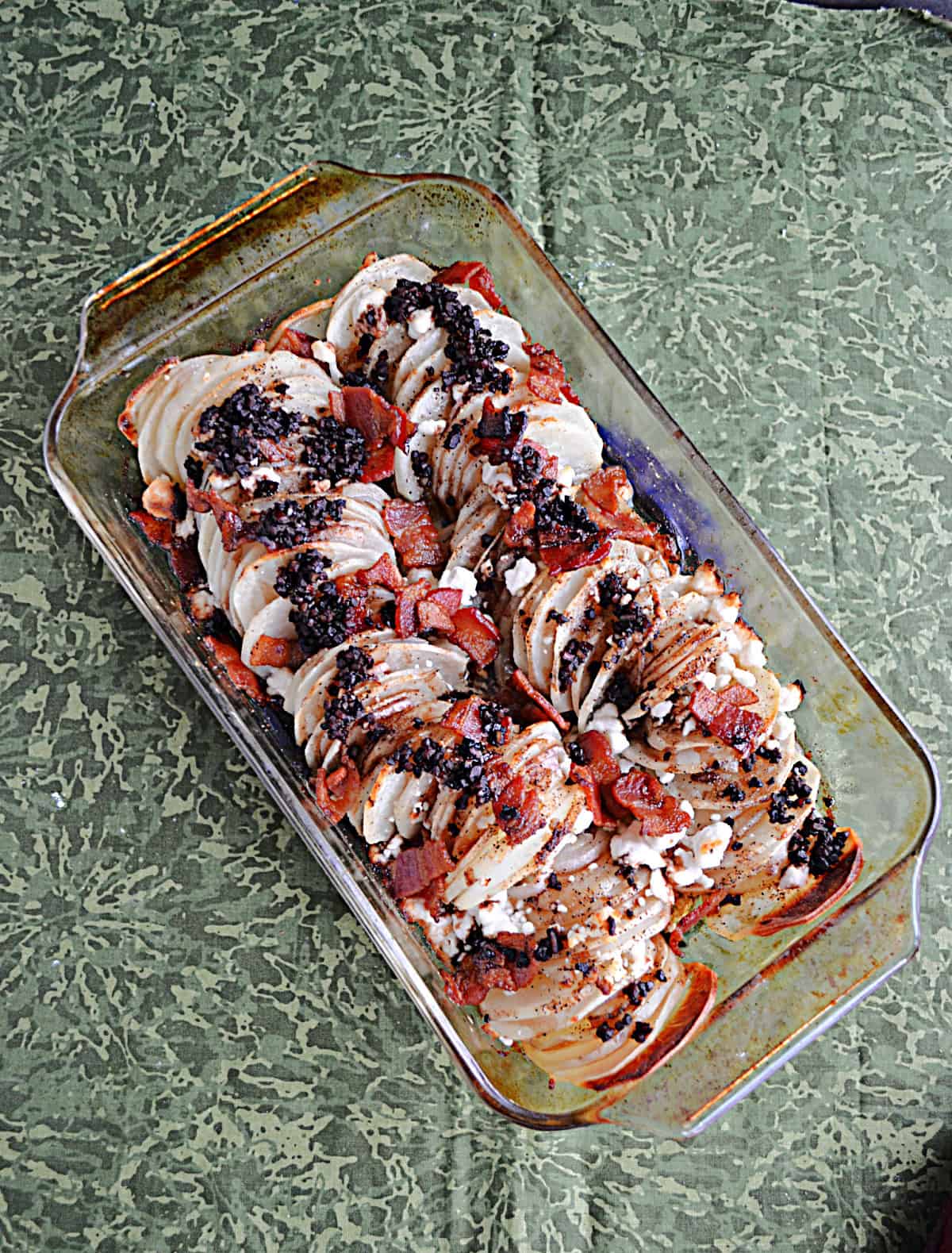 A baking pan with sliced potatoes and toppings.