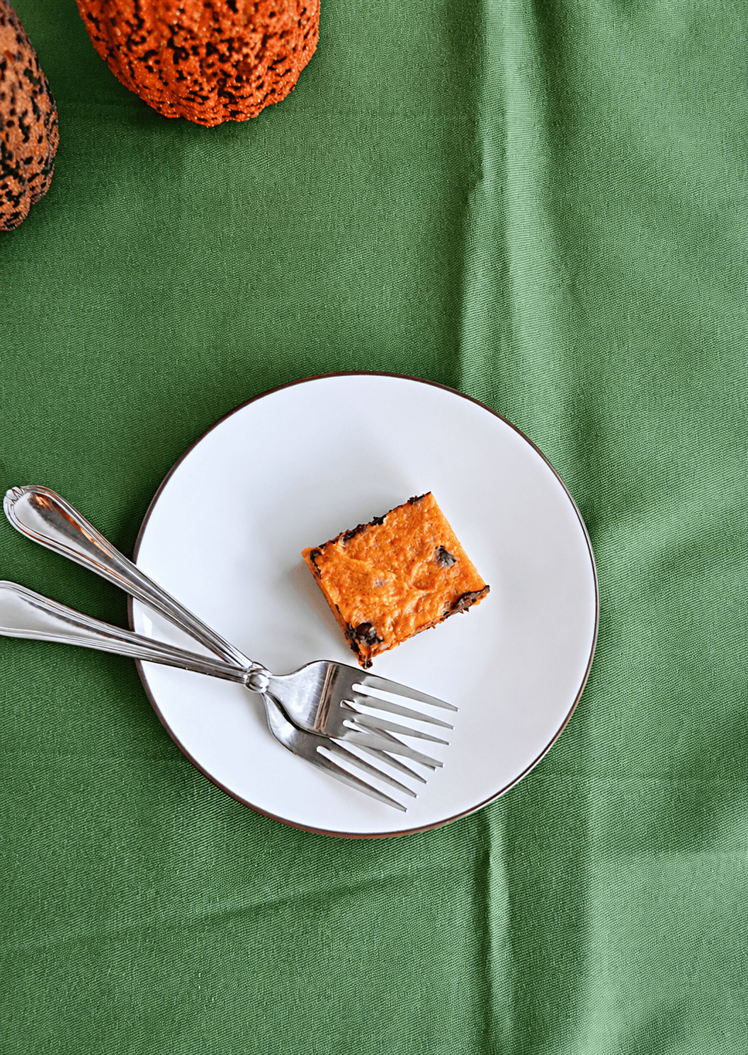 A top view of a plate with a pumpkin bar and 2 forks on it.