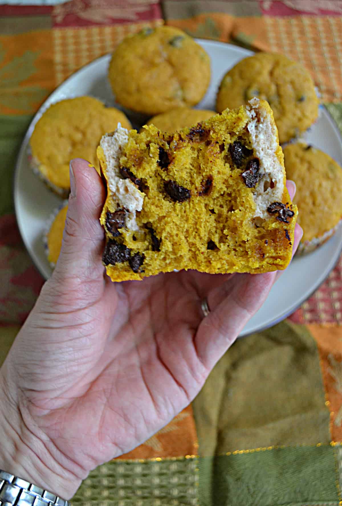 A hand holding a muffin that is broken open.