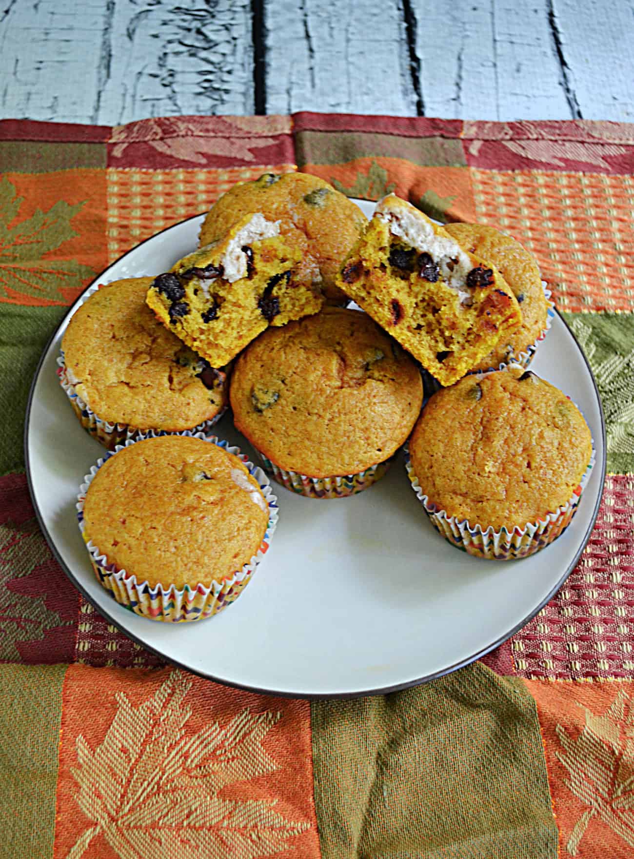 A plate of pumpkin muffins with a muffin broken open on top.