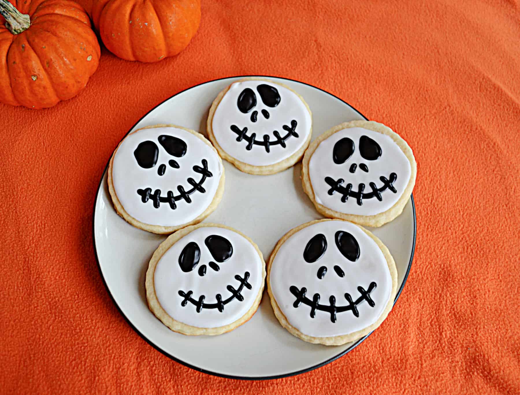 A plate with 5 Jack Skellington face cookies on it.