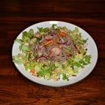 A chopped Asian salad topped with Noodles and Pork in an Asian Sauce