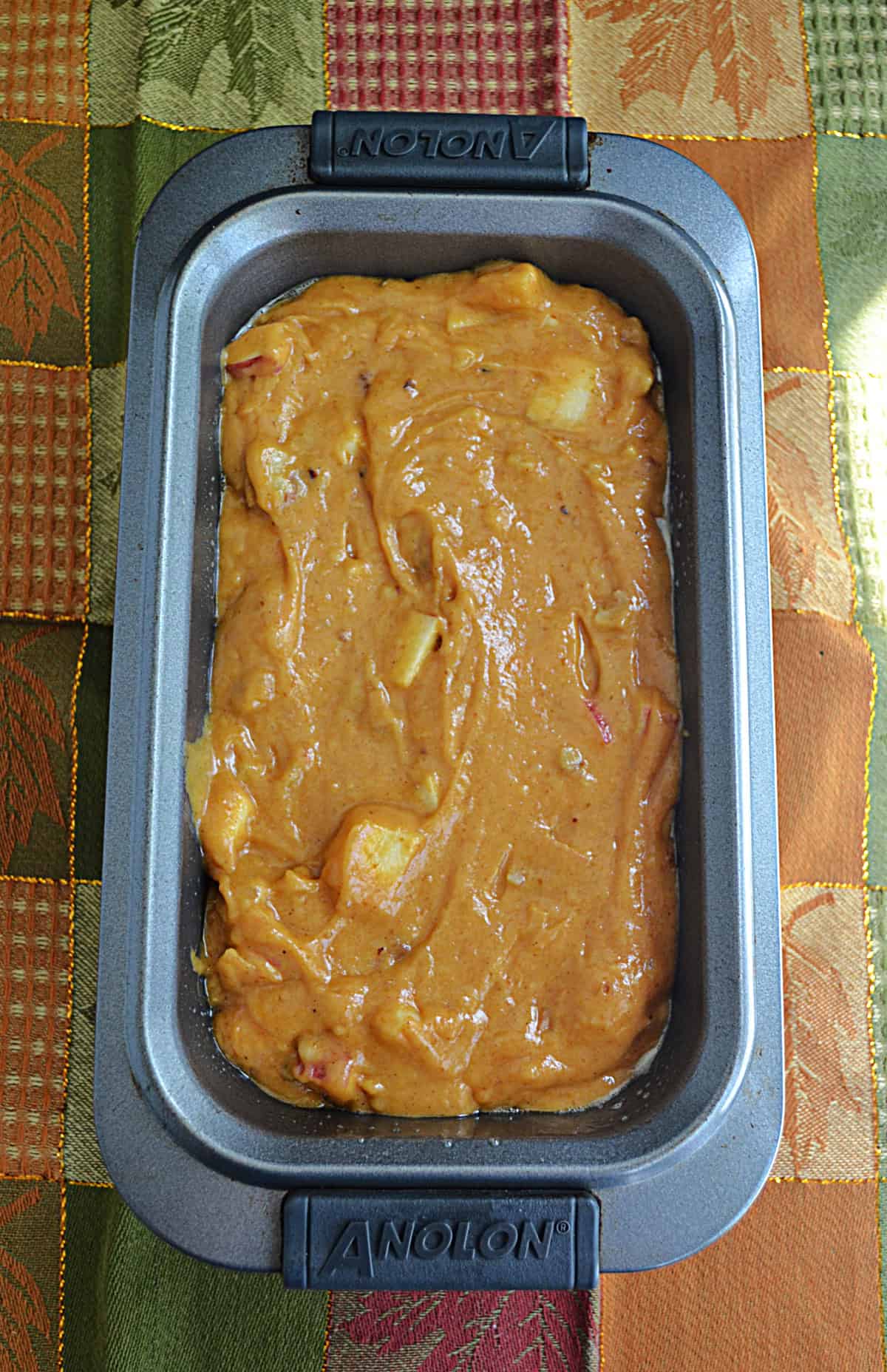 A loaf pan with apple bread batter in it.