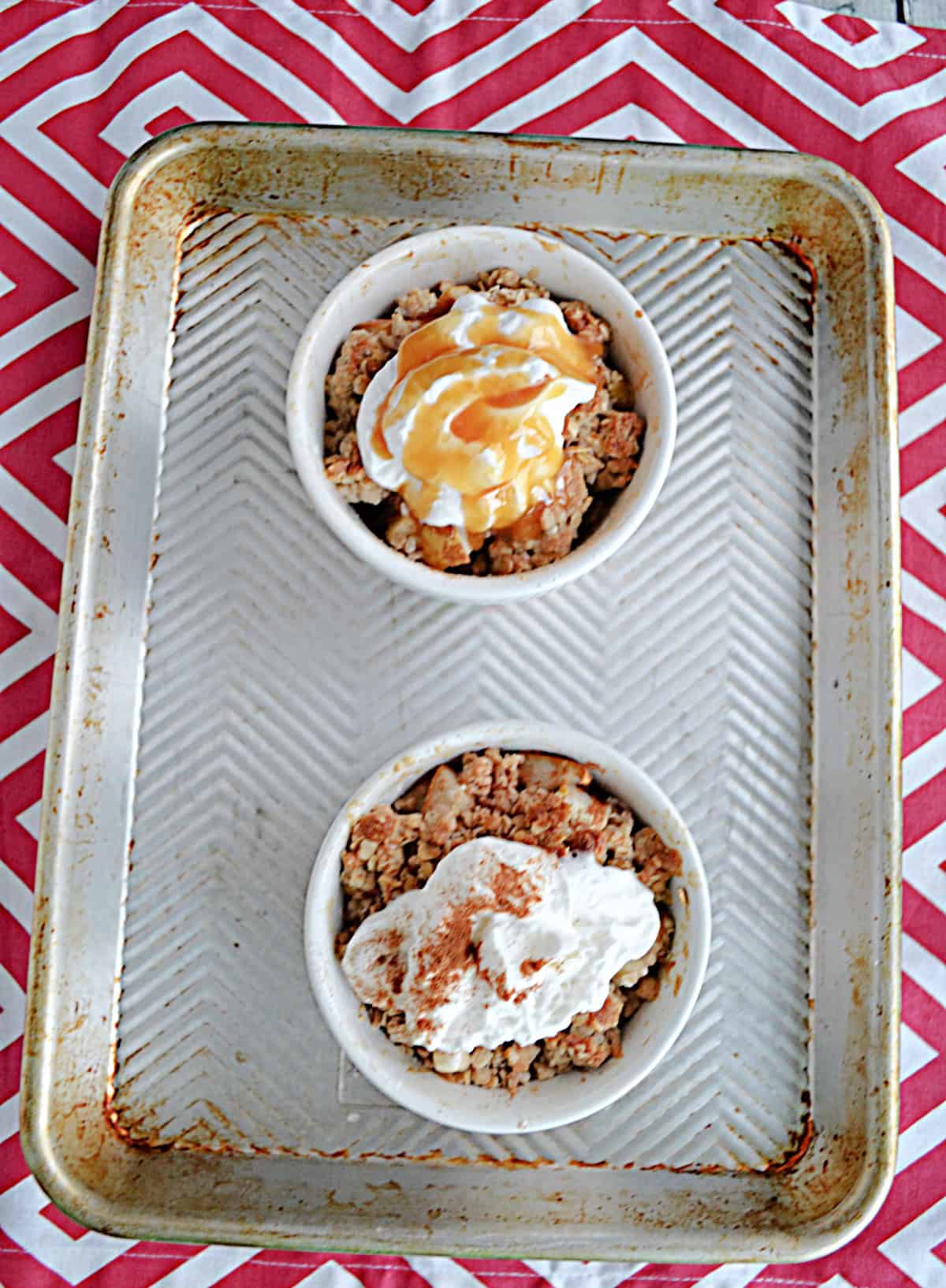 Two dishes of Apple Pear Crisp with whipped cream and caramel on top.