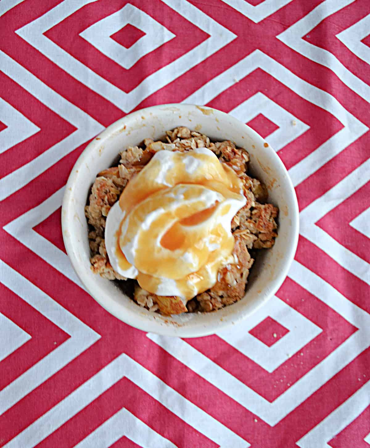 A bowl of Apple Pear crisp with whipped cream, caramel, and cinnamon on top. 