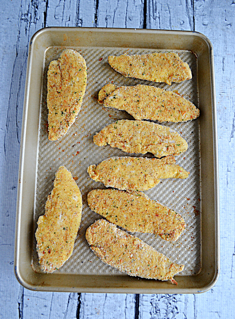 Breaded chicken fingers on a baking sheet.