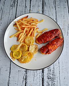 A plate with a pile of fries, a scoop of yellow squash, and two BBQ chicken tenders.