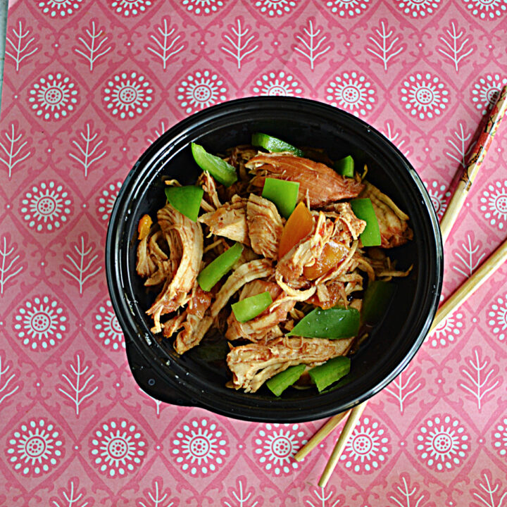 A bowl filled with chicken and green peppers with chopsticks next to the bowl.