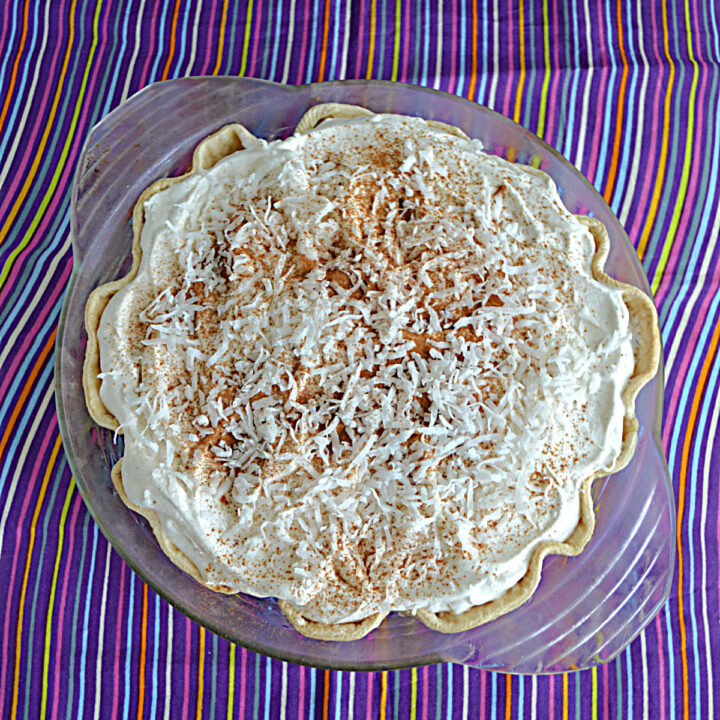 A pie topped with whipped cream, cinnamon, and coconut.