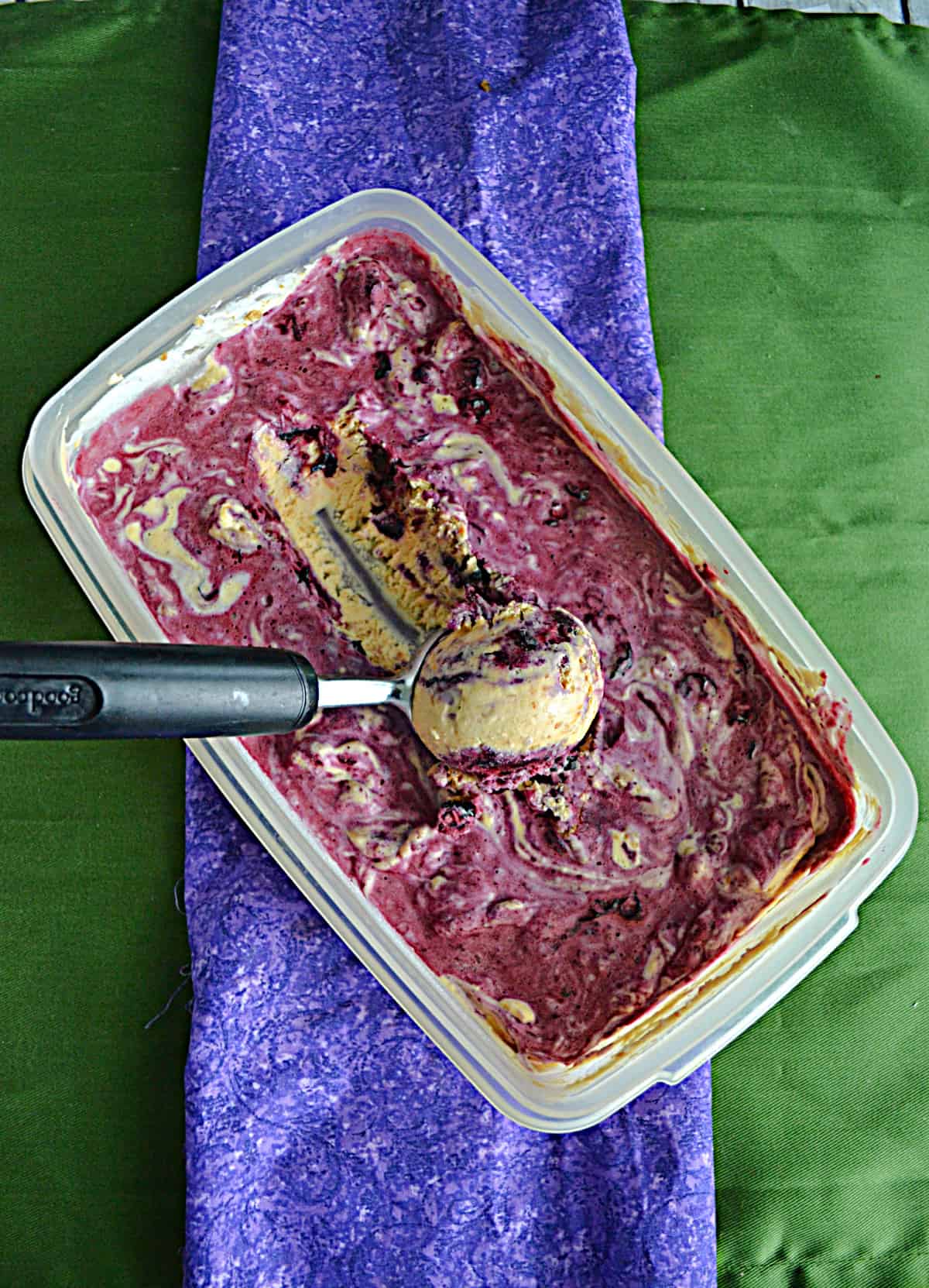 A container of blueberry ice cream with an ice cream scoop in it.