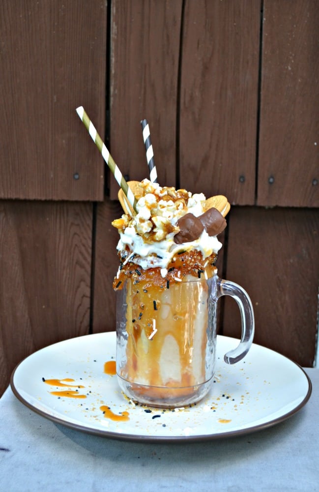 You are going to love the flavors in this Salted Caramel Cookie Monster Milkshake topped with whipped cream, candy bars, caramel popcorn, and vanilla cookies.